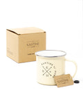 Camping-Tasse: beiger Emaille-Becher mit Metallrand und Deckel, neben Karton