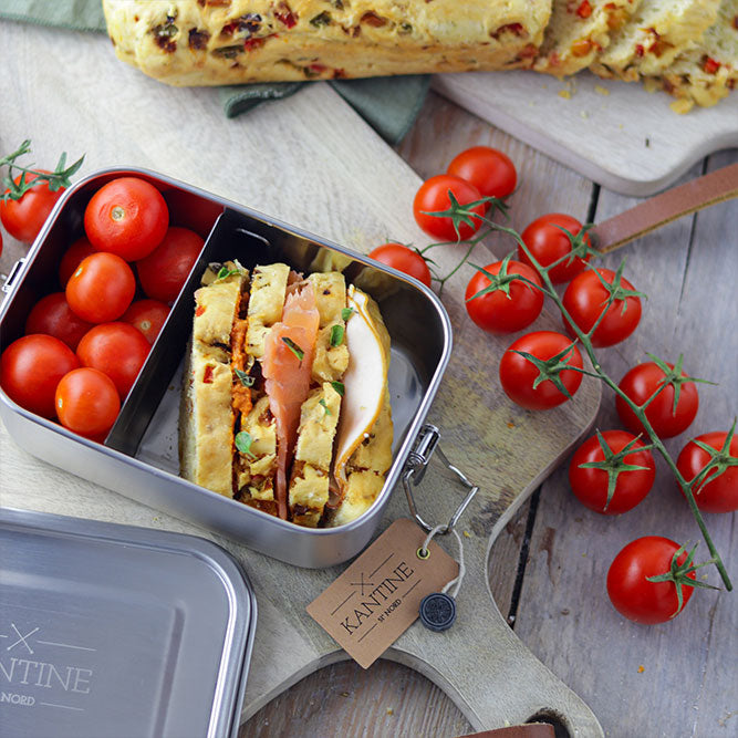 Edelstahl-Lunchbox mit Klappdeckel, gefüllt mit Sandwich und Kirschtomaten