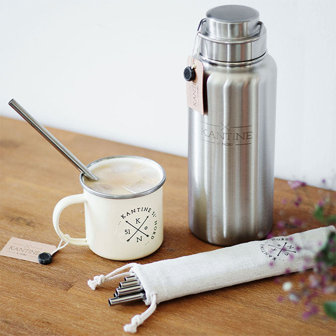 Isolierflasche Milkman aus Edelstahl, silber mit Deckel, neben Becher und Löffel
