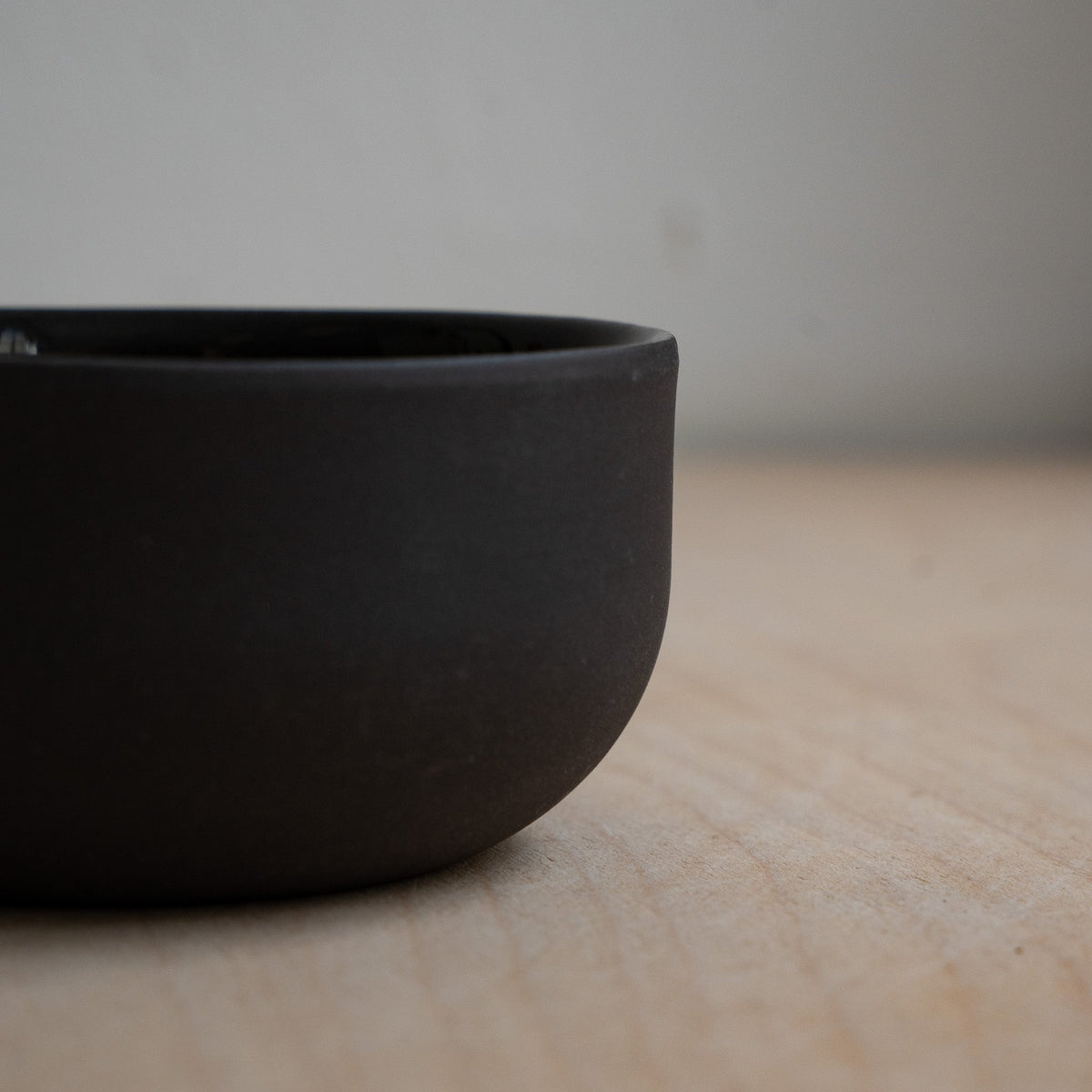 Schwarze Cappuccino-Tasse, seitlicher Blick auf glatte, matte Keramikoberfläche