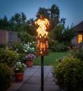 Gartenfackel mit Vogelmotiv, Metallzylinder und Flammen auf schwarzem Ständer
