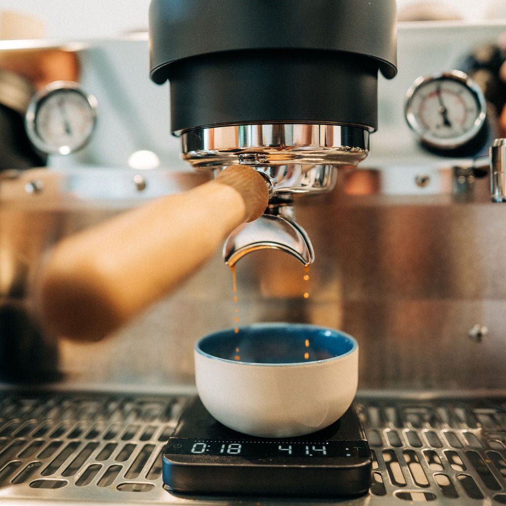 Beige Keramik-Tasse mit blauem Innen, unter einem Siebträger