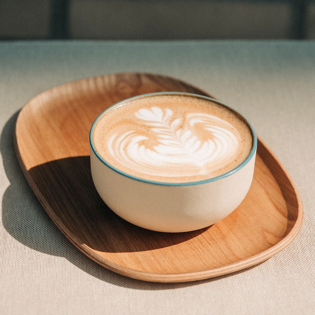 Beige Keramik-Tasse mit blauem Innen und Latte-Art im Tasseninneren