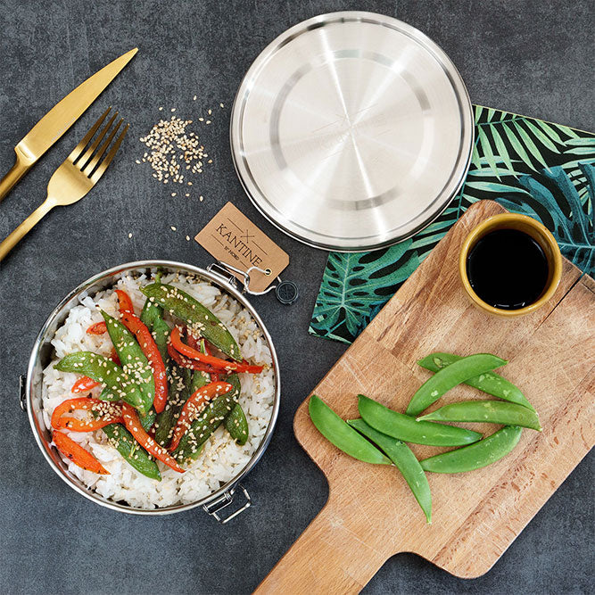 Edelstahl-Lunchbox mit geöffnetem Deckel, Salat und Gemüse im Innenbehälter