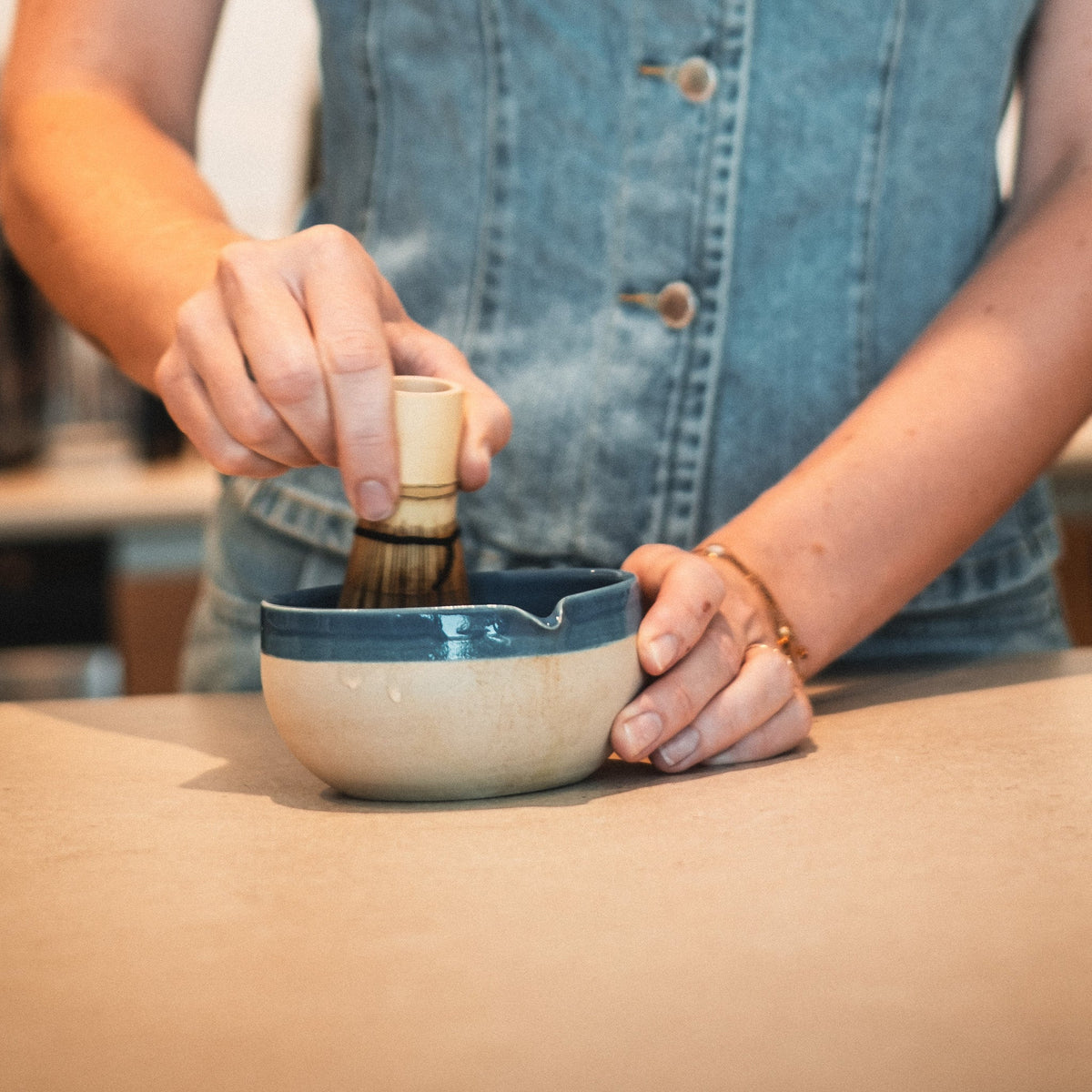 Blaues Matcha-Schälchen mit Bambusbesen, Person rührt im Schälchen