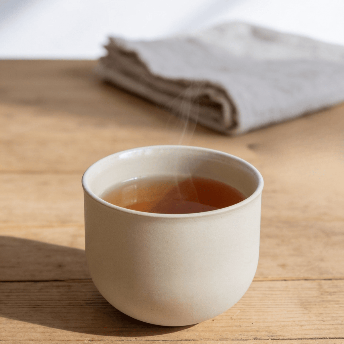 Beige Teetasse auf Holzbrett, Heißgetränk sichtbar
