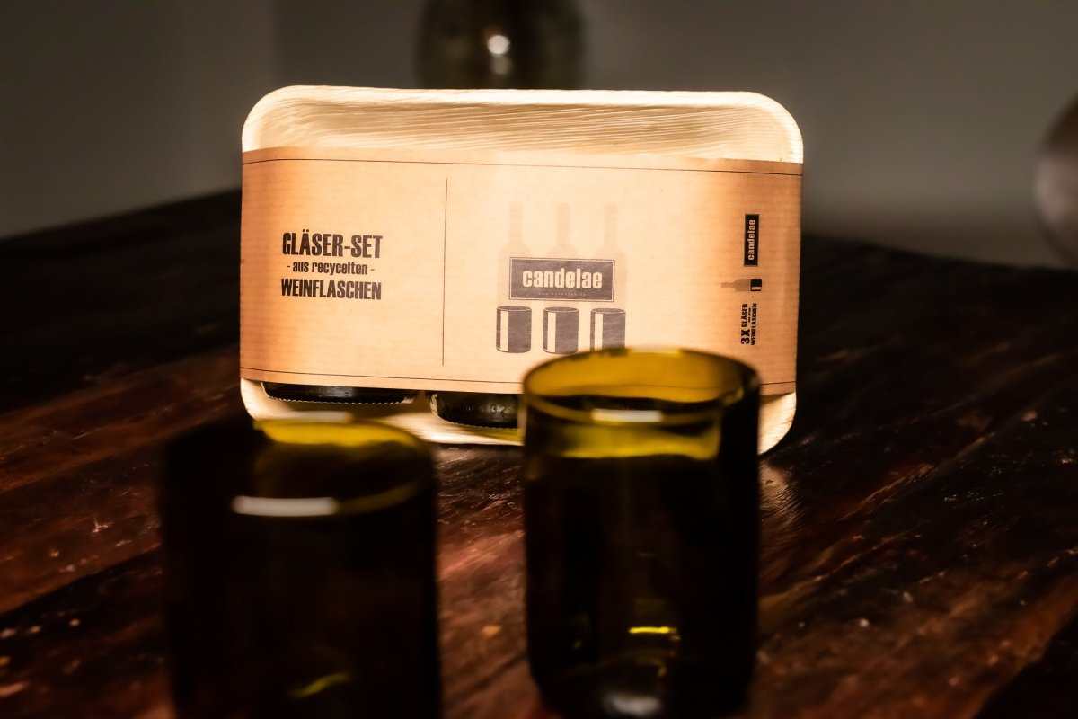 Trinkgläser-Set: Karton mit candelae-Aufdruck und mehrere grüne Gläser auf Holz