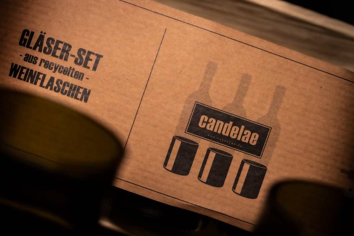 Karton mit Aufdruck „GLÄSER-SET“ und candelae-Logo, daneben grünes Glas